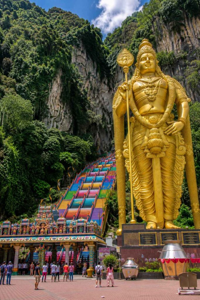Best Things to Do in Malaysia for First-Time Visitors (Complete Guide) 8 Golden Murugan statue at Batu Caves temple entrance with rainbow stairs